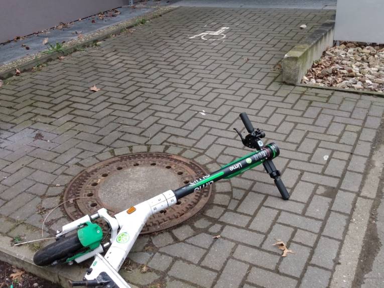Elektro-Roller liegt auf dem Gehweg